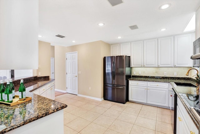 kitchen featuring freestanding refrigerator, visible vents, a sink, and white cabinetry