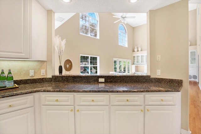 kitchen featuring white cabinets, ceiling fan, visible vents, and dark stone countertops