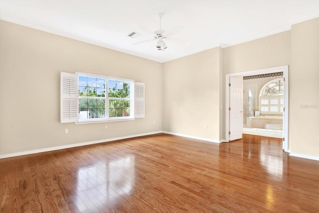 empty room featuring a ceiling fan, visible vents, baseboards, and wood finished floors