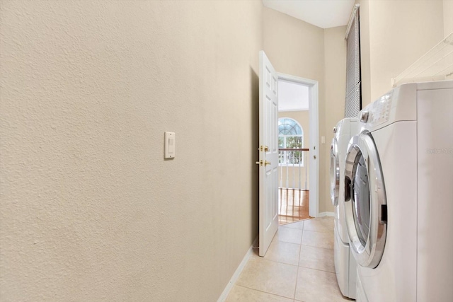 laundry room featuring light tile patterned floors, laundry area, washing machine and clothes dryer, and baseboards