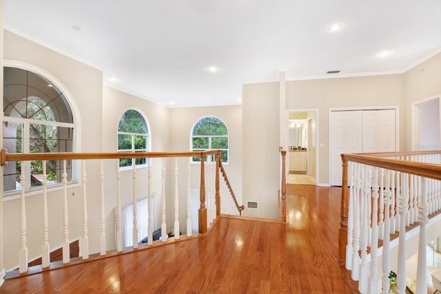 hallway with recessed lighting, visible vents, wood finished floors, and an upstairs landing