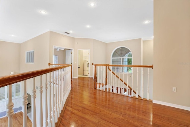 corridor with recessed lighting, an upstairs landing, wood finished floors, washer / dryer, and baseboards