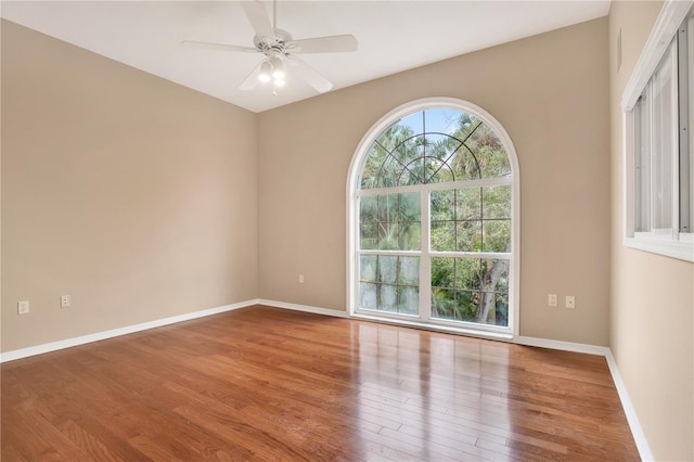 empty room with ceiling fan, baseboards, and wood finished floors