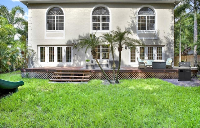 back of house featuring a yard, a deck, stucco siding, and french doors