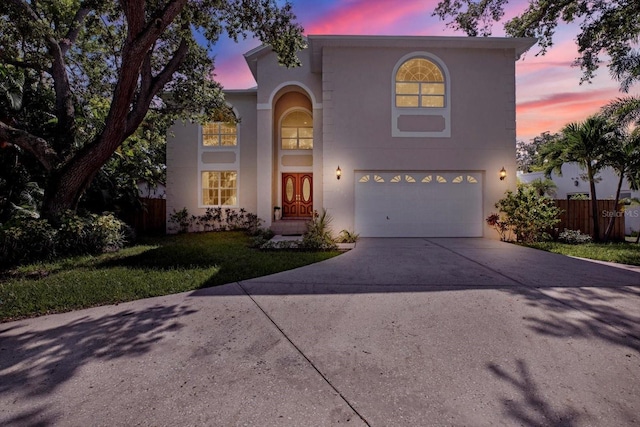 view of front of house featuring stucco siding, driveway, fence, a front yard, and an attached garage