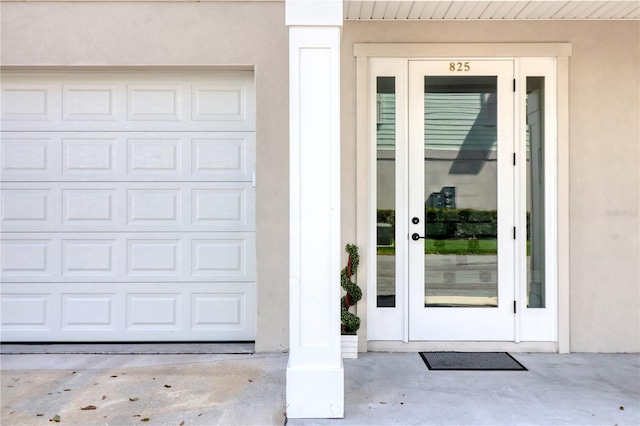 property entrance with a garage and stucco siding