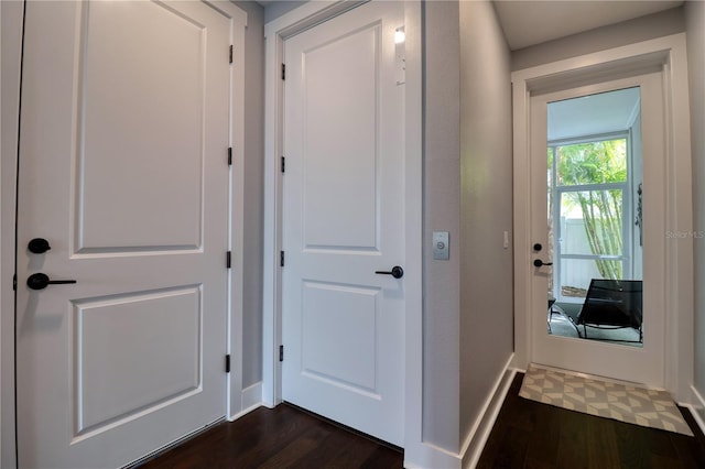 doorway featuring baseboards and dark wood finished floors