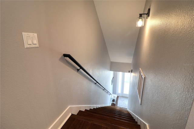 stairway with a textured wall, baseboards, and wood finished floors