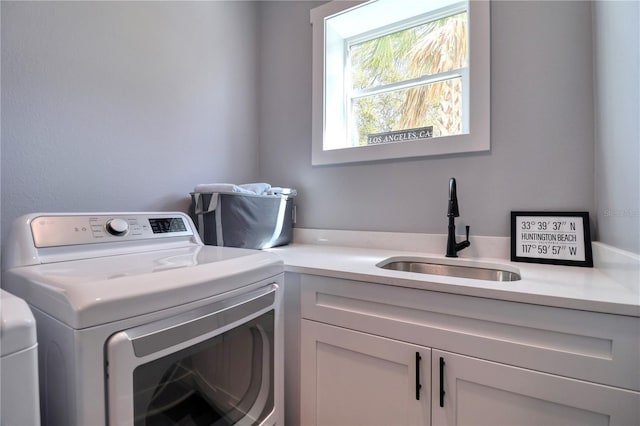 clothes washing area featuring cabinet space, separate washer and dryer, and a sink