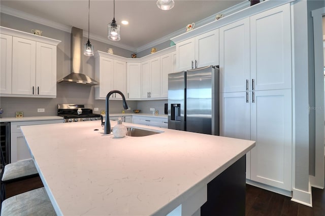 kitchen featuring a sink, ornamental molding, range, wall chimney exhaust hood, and stainless steel fridge