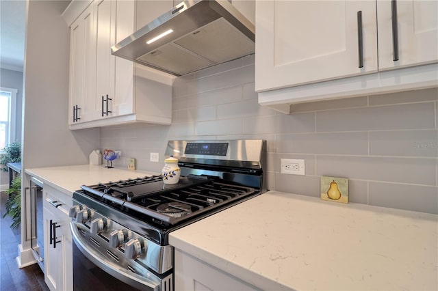 kitchen featuring stainless steel gas range, exhaust hood, backsplash, and white cabinets