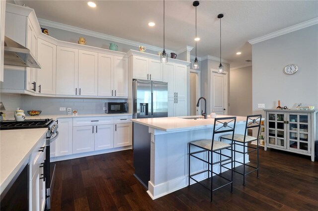 kitchen with wall chimney exhaust hood, appliances with stainless steel finishes, dark wood finished floors, and a sink