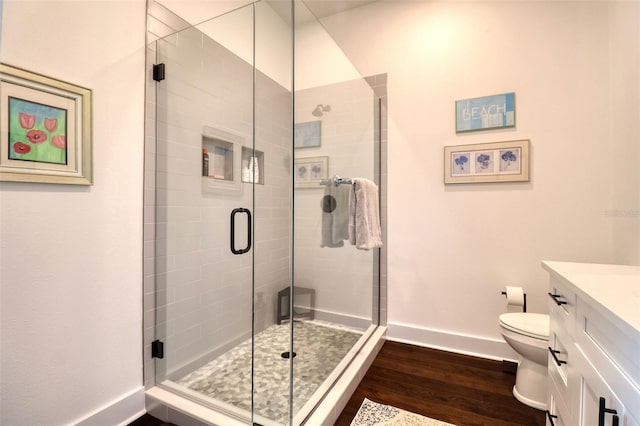 full bath featuring baseboards, toilet, wood finished floors, vanity, and a shower stall