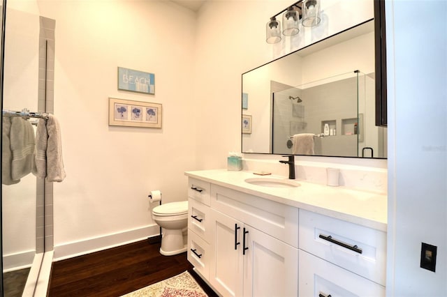 full bath featuring a stall shower, baseboards, toilet, wood finished floors, and vanity