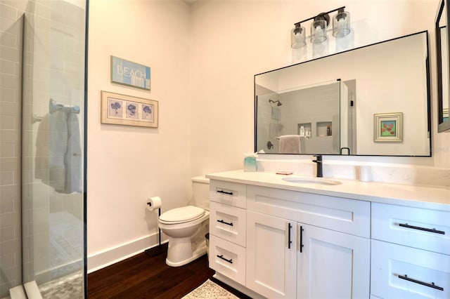 full bathroom featuring baseboards, toilet, wood finished floors, vanity, and a shower stall