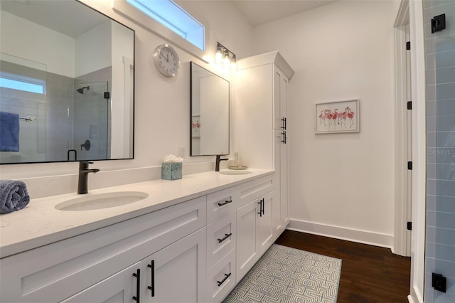 full bathroom featuring double vanity, wood finished floors, a sink, and a shower stall