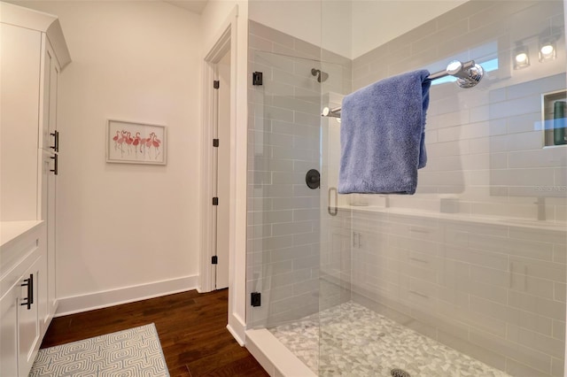 bathroom with a shower stall, baseboards, and wood finished floors