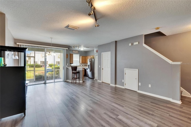 unfurnished living room featuring stairway, wood finished floors, and visible vents