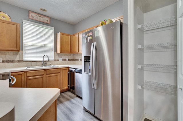 kitchen featuring tasteful backsplash, stainless steel appliances, a sink, and light countertops