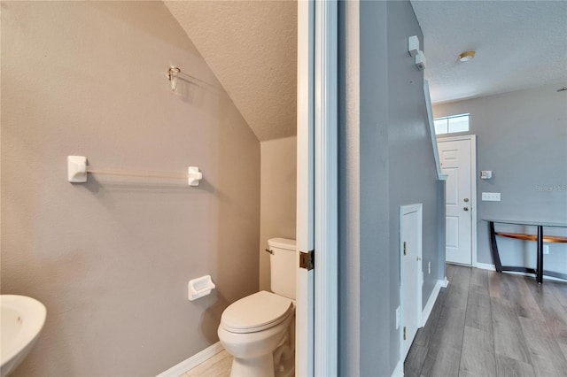 bathroom with toilet, baseboards, and wood finished floors