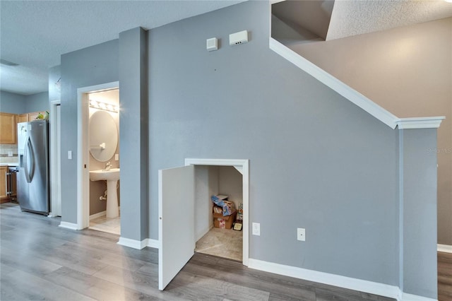 unfurnished living room featuring a textured ceiling, wood finished floors, and baseboards