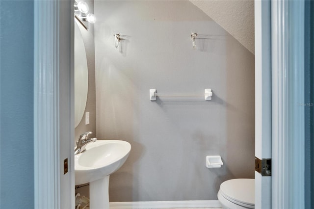 half bath with a sink, toilet, and baseboards