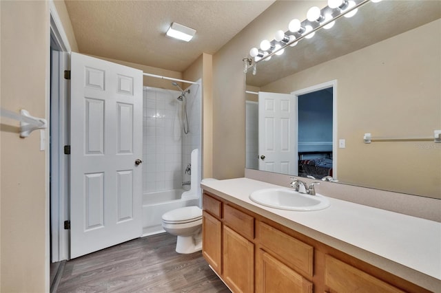 bathroom with toilet, connected bathroom, vanity, a textured ceiling, and wood finished floors