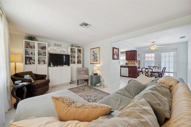 living room with a ceiling fan, visible vents, and light tile patterned floors