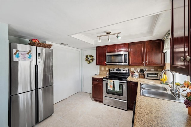 kitchen with a raised ceiling, appliances with stainless steel finishes, a sink, and tasteful backsplash