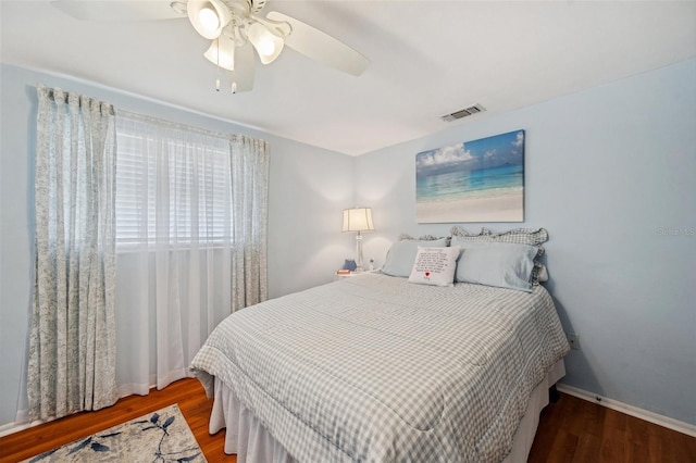 bedroom with baseboards, wood finished floors, visible vents, and a ceiling fan