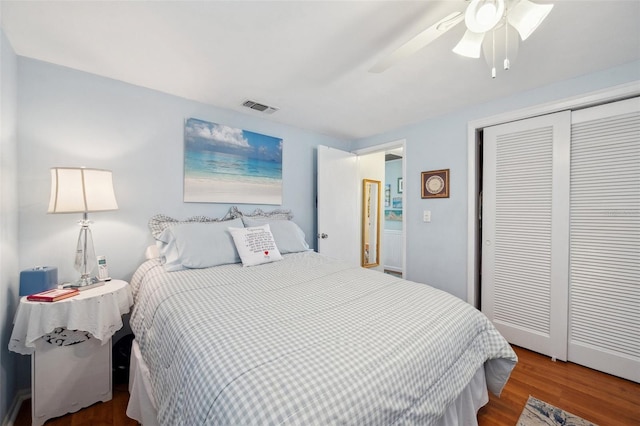 bedroom with a closet, wood finished floors, visible vents, and a ceiling fan