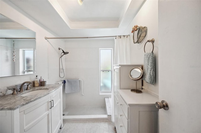 bathroom featuring a raised ceiling, tiled shower, vanity, and tile patterned floors