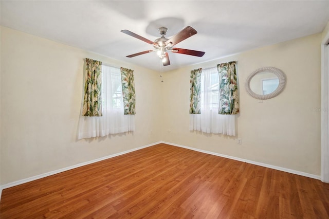 spare room featuring a ceiling fan, baseboards, and wood finished floors