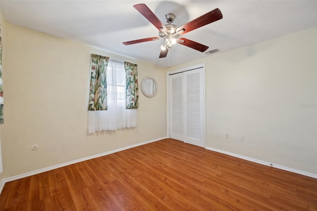 unfurnished bedroom with baseboards, visible vents, ceiling fan, wood finished floors, and a closet