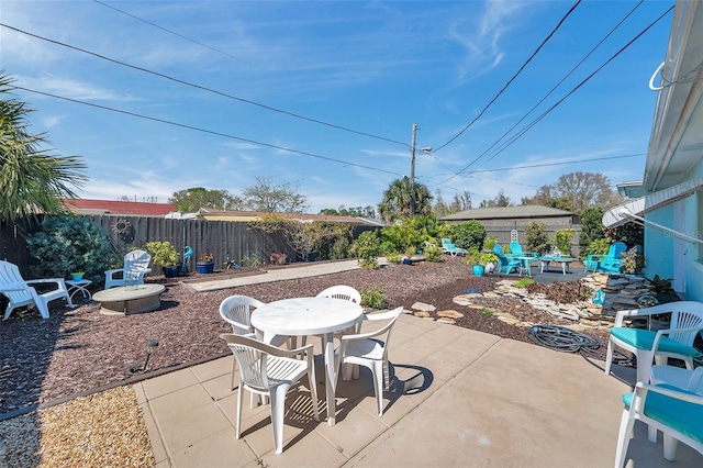 view of patio featuring fence, a fire pit, and outdoor dining area