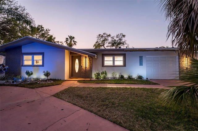 view of front of home with an attached garage, a yard, driveway, and stucco siding