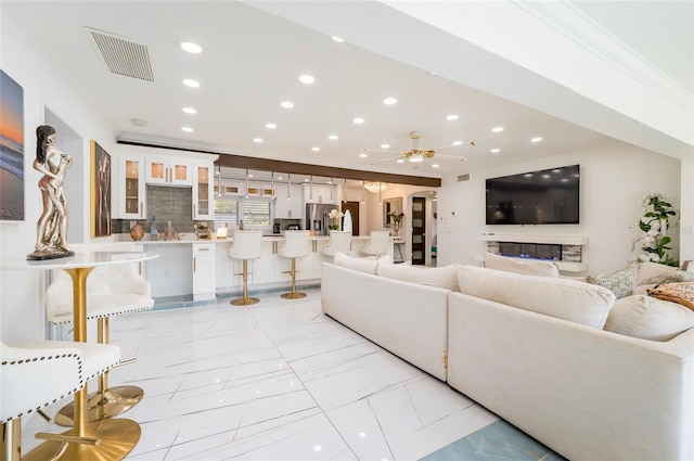 living area with a ceiling fan, visible vents, recessed lighting, crown molding, and marble finish floor