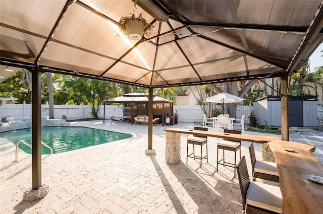 view of pool with a gazebo, a fenced backyard, an outdoor structure, a patio area, and a storage unit