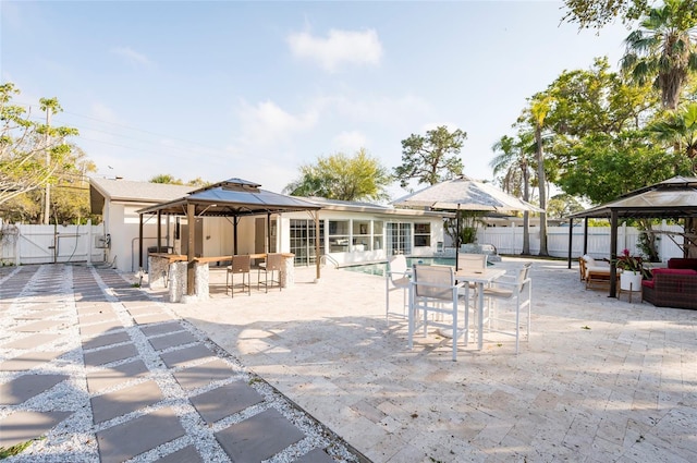 view of patio / terrace featuring a gazebo, outdoor dining area, a fenced backyard, and a gate