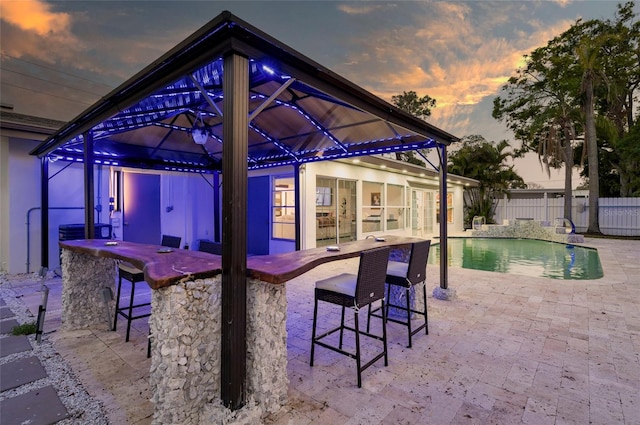 view of patio / terrace with outdoor dry bar, a fenced in pool, a gazebo, and fence