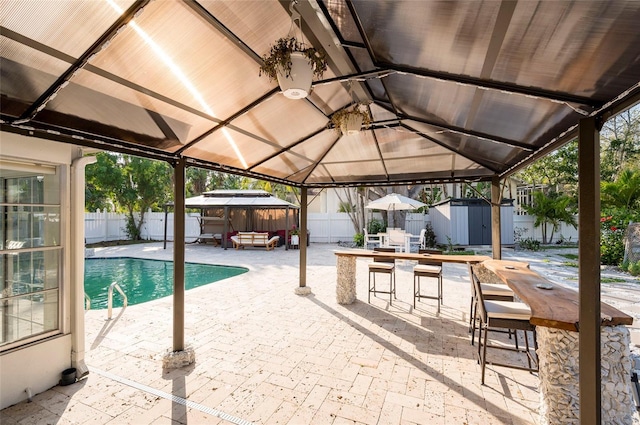 view of swimming pool featuring a storage unit, an outbuilding, a patio, a fenced backyard, and a gazebo