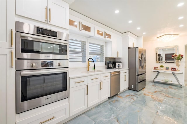 kitchen featuring glass insert cabinets, recessed lighting, appliances with stainless steel finishes, white cabinetry, and a sink