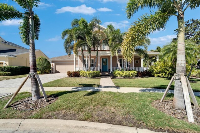 5616 Seagrass Pl, Apollo Beach, FL 33572 - view of front of property featuring decorative driveway, a porch, an attached garage, a balcony, and a front lawn