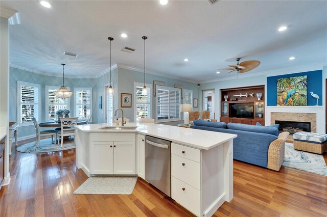 5616 Seagrass Pl, Apollo Beach, FL 33572 - kitchen with light wood finished floors, visible vents, stainless steel dishwasher, a glass covered fireplace, and a sink