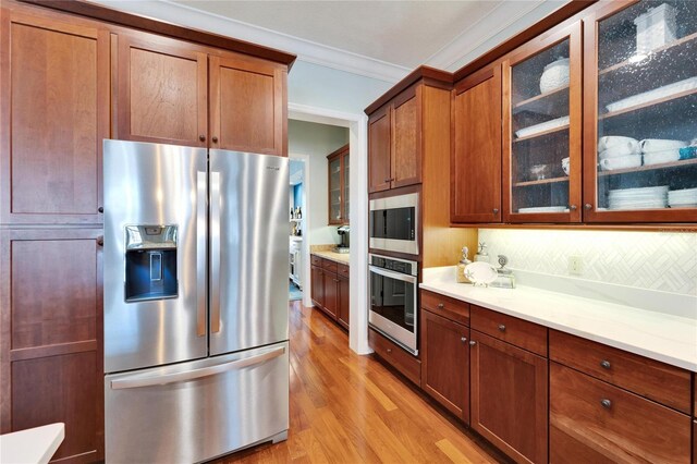 5616 Seagrass Pl, Apollo Beach, FL 33572 - kitchen featuring light wood finished floors, glass insert cabinets, stainless steel appliances, crown molding, and light countertops