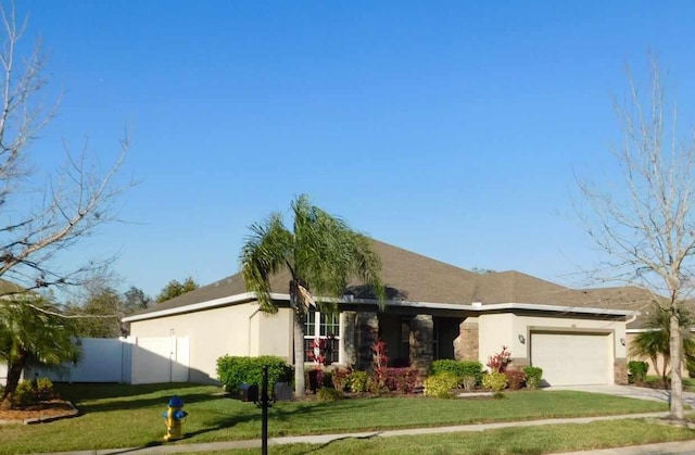 ranch-style house with a garage, fence, concrete driveway, stucco siding, and a front yard