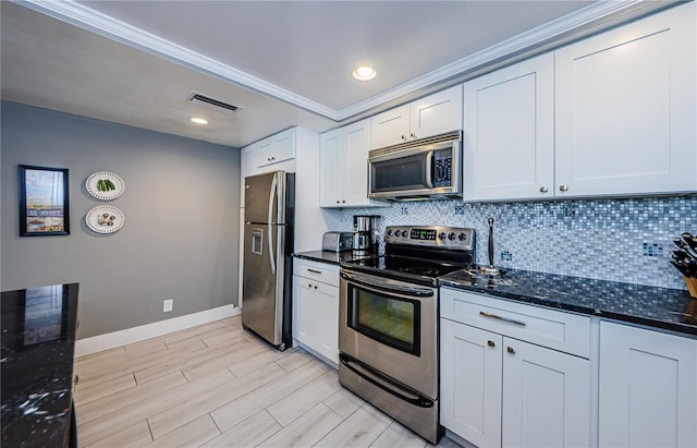 kitchen featuring dark stone countertops, visible vents, wood finish floors, appliances with stainless steel finishes, and backsplash