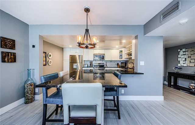 dining room featuring light wood-style flooring, a notable chandelier, baseboards, and visible vents