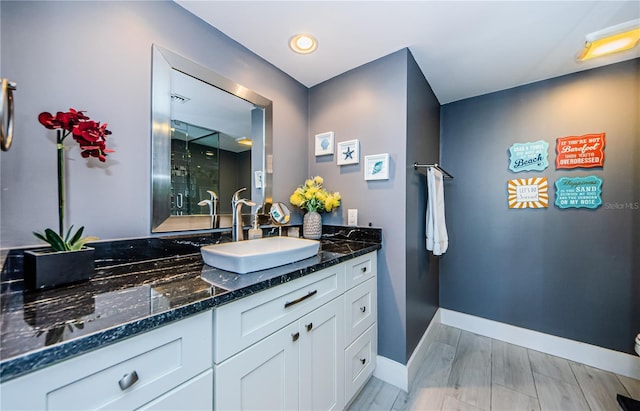 full bathroom with vanity, wood finished floors, baseboards, and a shower