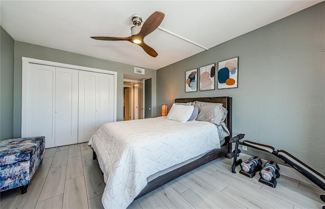 bedroom featuring a ceiling fan, visible vents, a closet, and wood finish floors